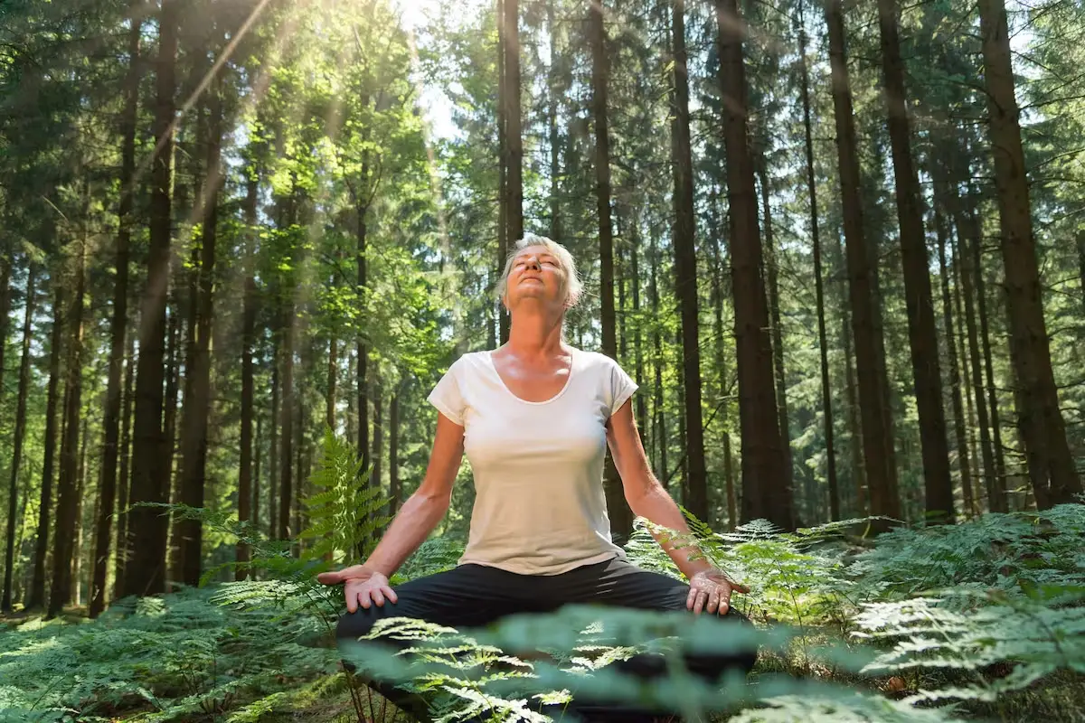 Mujer meditando en medio del bosque.