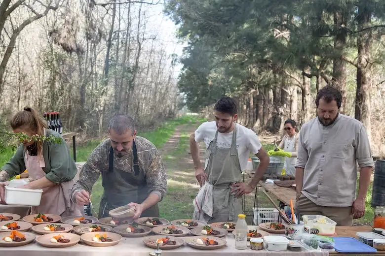 Personas cocinando con productos regionales en medio del bosque.
